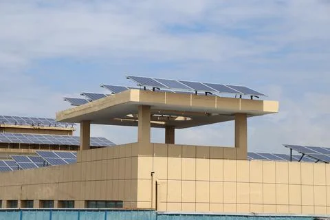 Solar panel arrays mounted on raised rooftop structures of large beige buil.. Stock Photos