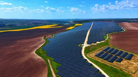 Solar panel arrays stretching between plowed farmland and rapeseed crops. Stock-Footage 337064207