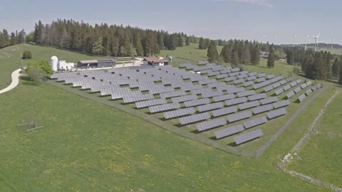 Solar panel assembly on a green, grassy mountain under a blue sky, aerial 4k Video stock 130181740