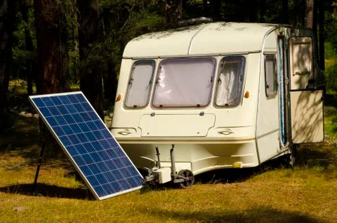 Solar panel in a camping with old caravan on the river bank Stock Photos