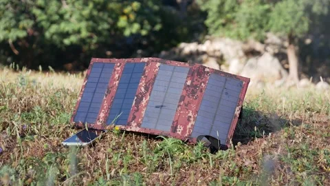The solar panel that charges the phone is illuminated by the rays of the risi Vídeos de archivo 166091436