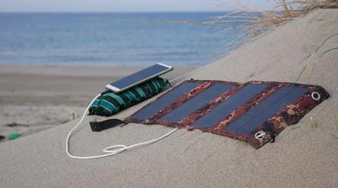 The solar panel charges the smartphone in the sands against the background of 스톡 사진