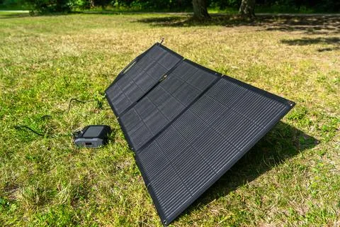 Solar panel connected to portable power station in open air. Sustainable outd Stock Photos