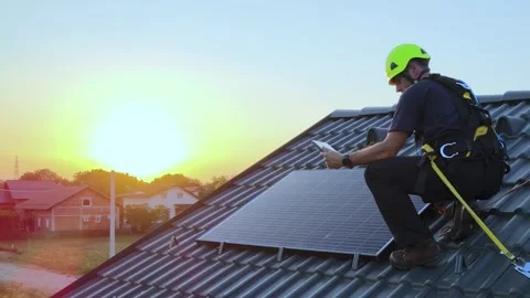 Solar panel engineer inspecting photovoltaic system on rooftop at sunset Stock Footage 339645515