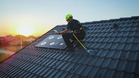 Solar panel engineer installing a photovoltaic cell on a house roof Stock Photos