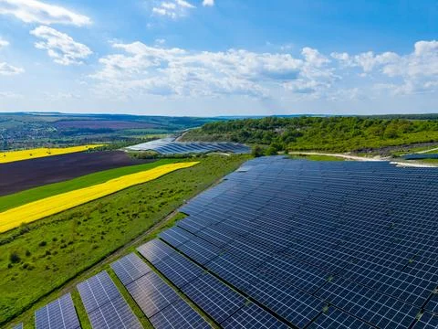 A solar panel field covers a large area of farmland with bright yellow fields 스톡 사진