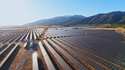 Solar panel field in a large open area under clear blue sky in mountainous Stock Footage 347763281