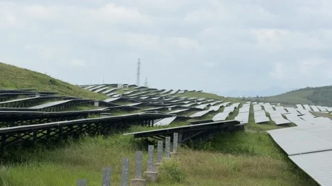 Solar panel grids stretch across grassy land while overhead clouds drift slowly Vídeo Stock 325034908