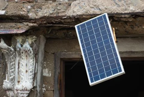 A solar panel hangs in the window of an old unmaintained building Stock Photos