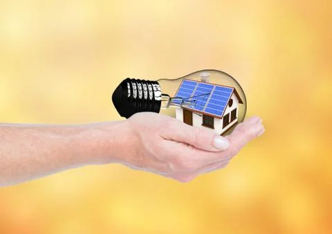 Solar panel house inside a light on hand. Orange/yellow background Foto stock