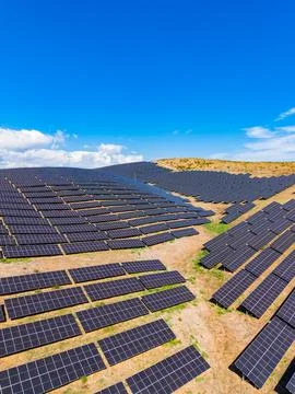 Solar panel installation covers large area in sunny landscape with blue sky.. Stock Photos