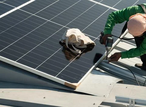 Solar panel installation on rooftop by technician during daytime Foto stock