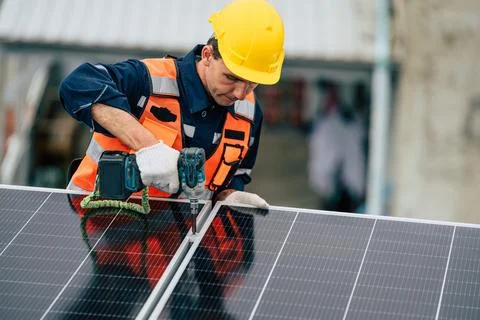 Solar panel installation by a worker on a rooftop during daylight Photos