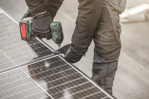 The solar panel installer twists the modules together using aluminum fasteners Stock Photos