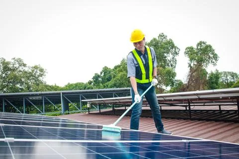Solar panel installers use brushes to clean dust from solar panels 库存照片
