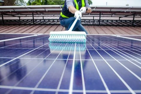 Solar panel installers use brushes to clean dust from solar panels Stock Photos