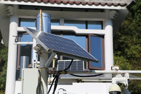 A solar panel is mounted on a pole next to a building Stock Photos