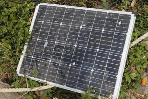 A solar panel with one black cell broken, lying on the ground, after being .. Stock Photos