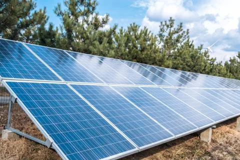 Solar panel over a blue sky and green trees. ecological alternative energy Stock Photos