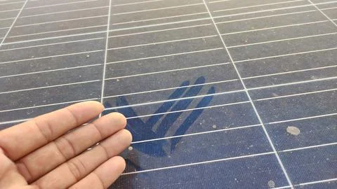 A solar panel surface covered with dust is shown, featuring a prominent handprin Stock Photos