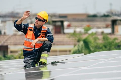 Solar panel technician inspecting installation on rooftop in a sunny urban .. Stock Photos