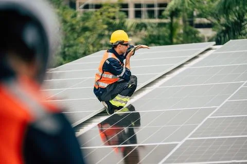 Solar panel technician performs maintenance on rooftop installation in urba.. Stock Photos