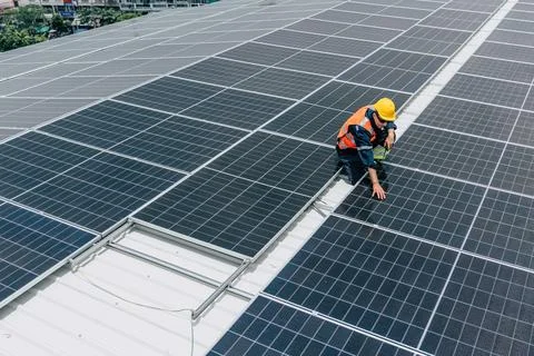 Solar panel technician performs maintenance work on rooftop installation in.. Stock Photos