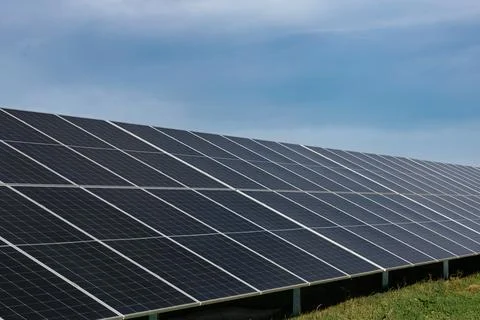 Solar panels absorbing sunlight under a cloudy blue sky Stock Photos