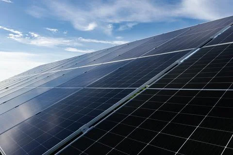Solar panels absorbing sunlight under a cloudy blue sky Stock Photos