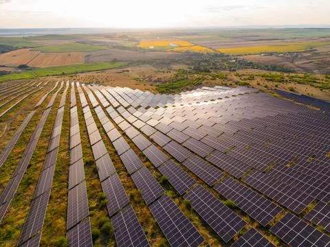 Solar panels are arranged in rows on a hillside. The scene shows fields and f Stock-Fotos