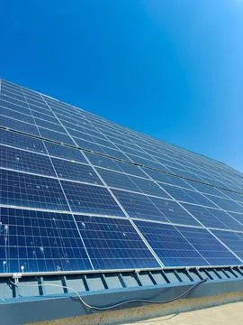 Solar panels are installed on a rooftop under a clear blue sky during the d.. 스톡 사진
