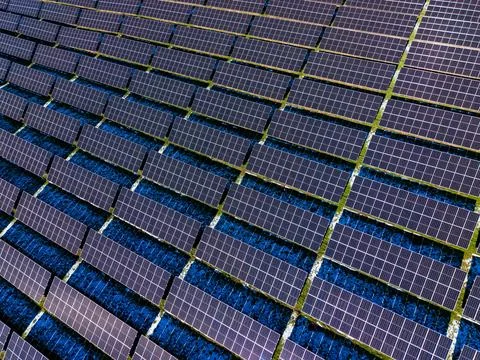 Solar panels are lined up in a grid pattern across an open area, capturing su Foto stock