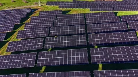 Solar panels arranged in a large field during daytime with green grass and blue Video stock 336525217