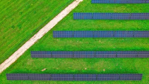 Solar panels arranged in neat rows across green fields in Latvia Stock Footage 319556014