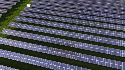 Solar panels arranged in neat rows on green land captured from above Stock Footage 325089915