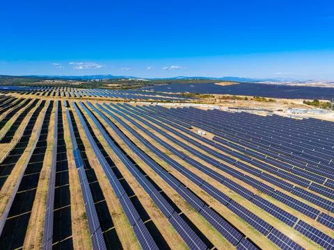 Solar panels arranged in rows at a solar farm located near a body of water .. Stock Photos