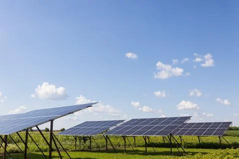 Solar panels on the background of a cloudy sky on a sunny day. Stock Photos