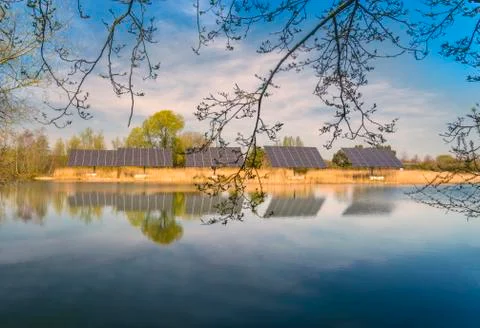 Solar panels bask in the sun over a Cotswold lake Stock Photos
