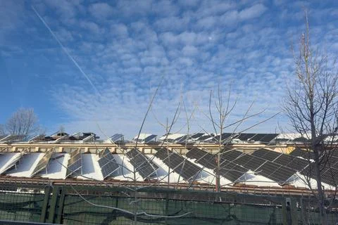 Solar Panels on Building Rooftops Under a Clear Blue Sky With Clouds on a S.. Stock Photos