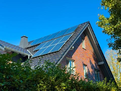 Solar panels capture sunlight on a charming brick house surrounded by vibra.. Stock Photos