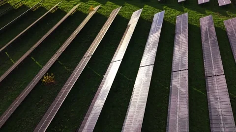 Solar panels capture sunlight in a green field from an aerial view Stock Footage 325090079