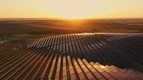 Solar panels collect sunlight on a field at sunset in an open landscape Vídeos de archivo 344775892