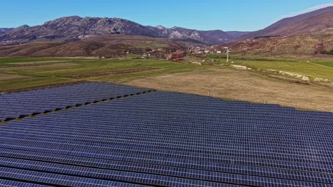 Solar panels cover fields in remote location with mountains in background 스톡 동영상 334030151