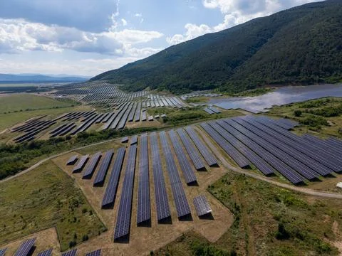 Solar panels cover fields in a vast landscape under cloudy sky Stock-Fotos
