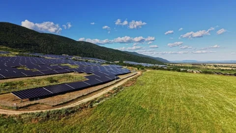 Solar panels cover a hillside under a blue sky in a rural area Stock Footage 339166095