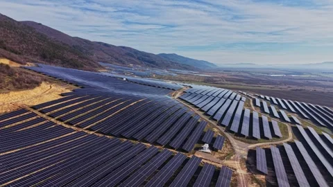 Solar panels cover large area in hilly landscape under blue sky Stock Footage 334032410