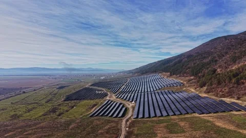 Solar panels cover a large area on a hillside near a valley Stockbeeldmateriaal 334032458