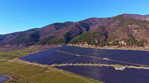 Solar panels cover large area on flat land near hills in bright sunlight during Stock Footage 335407032