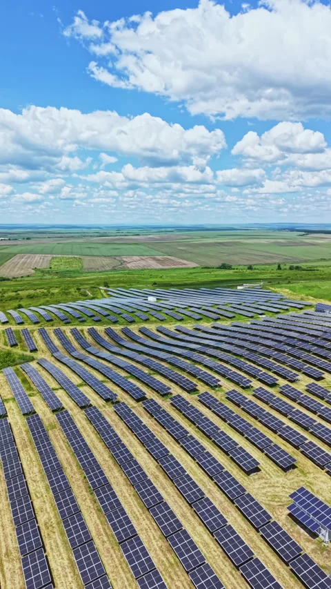 Solar panels cover a large area in an open field under a bright sky with clouds Video stock 337915123