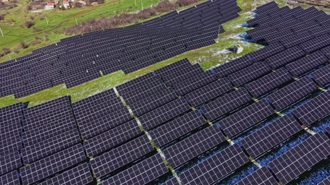 Solar panels cover a large area in a green landscape near a village 動画素材 337942879